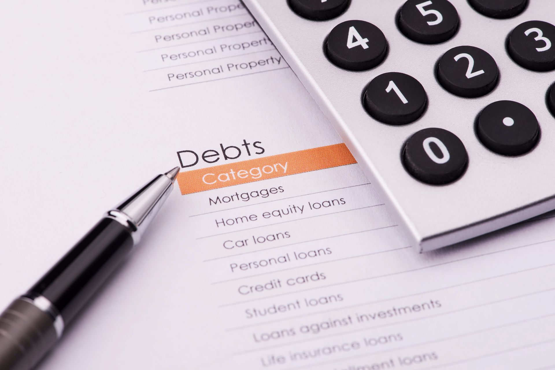 Pen and calculator on debt sheet with orange highlight