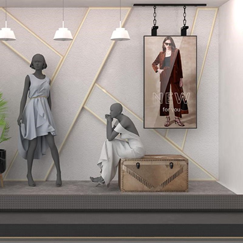 A mannequin is sitting on a trunk in front of a poster that says new