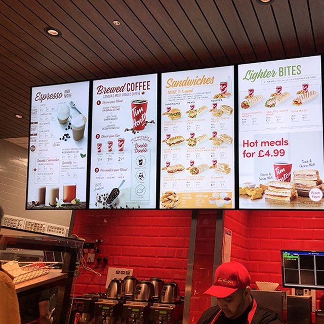 A man in a red hat is standing in front of a sign that says hot meals for 4.99