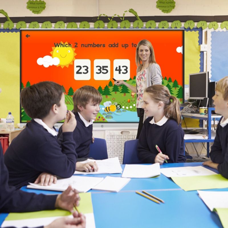 A group of children are sitting around a table in front of a screen that says which 2 numbers add up to 23 35 43