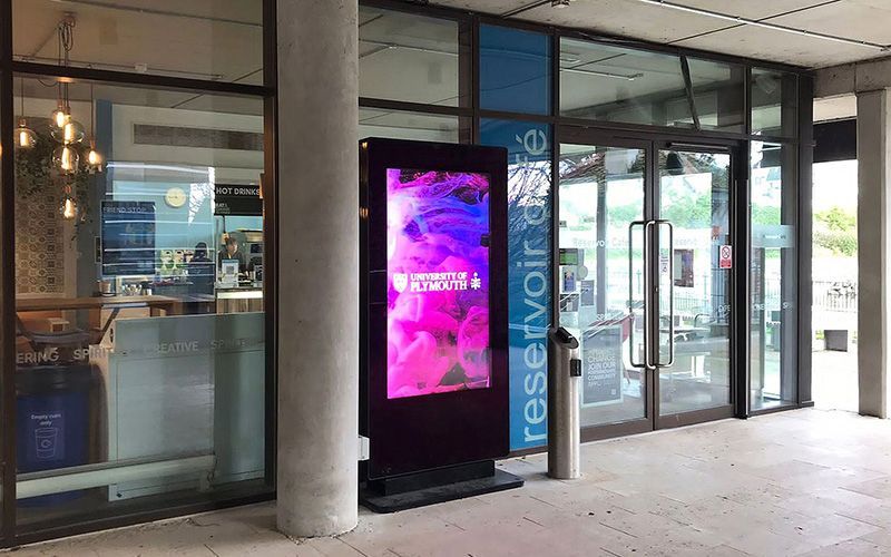Exterior view of a uni entrance with a digital display and glass doors.