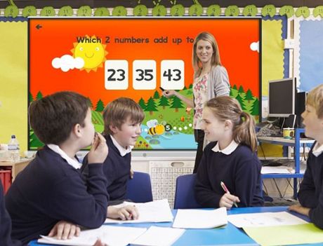 A group of children are sitting at a table in front of a screen that says which 2 numbers add up to 23 35 43