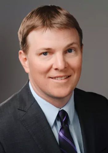 A man in a suit and tie is smiling for the camera.