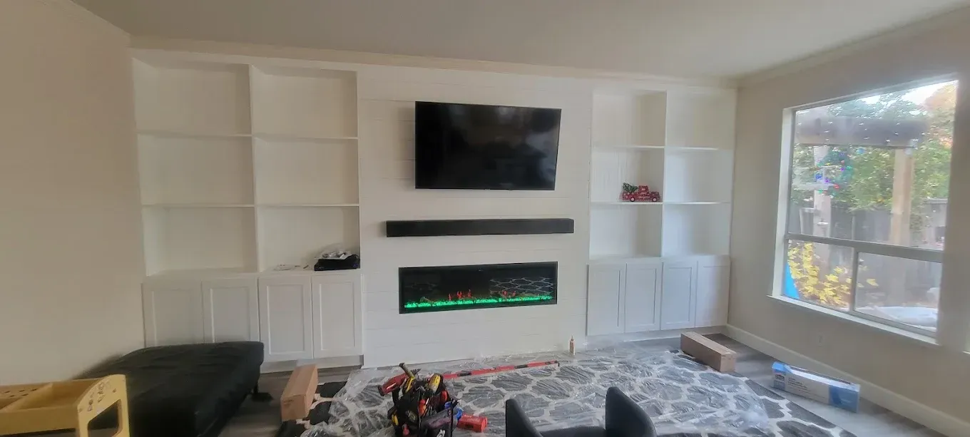 Living room with a built-in entertainment center, fireplace, and shelves, and window.