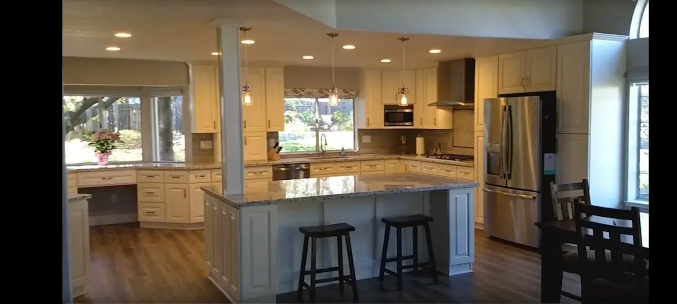Kitchen with white cabinets, island, stainless steel appliances, and hardwood floors.