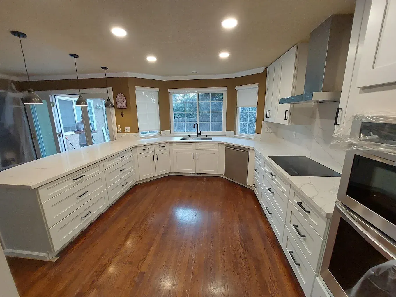 Newly renovated kitchen with white cabinets, dark countertops, stainless steel appliances, and wood floor.