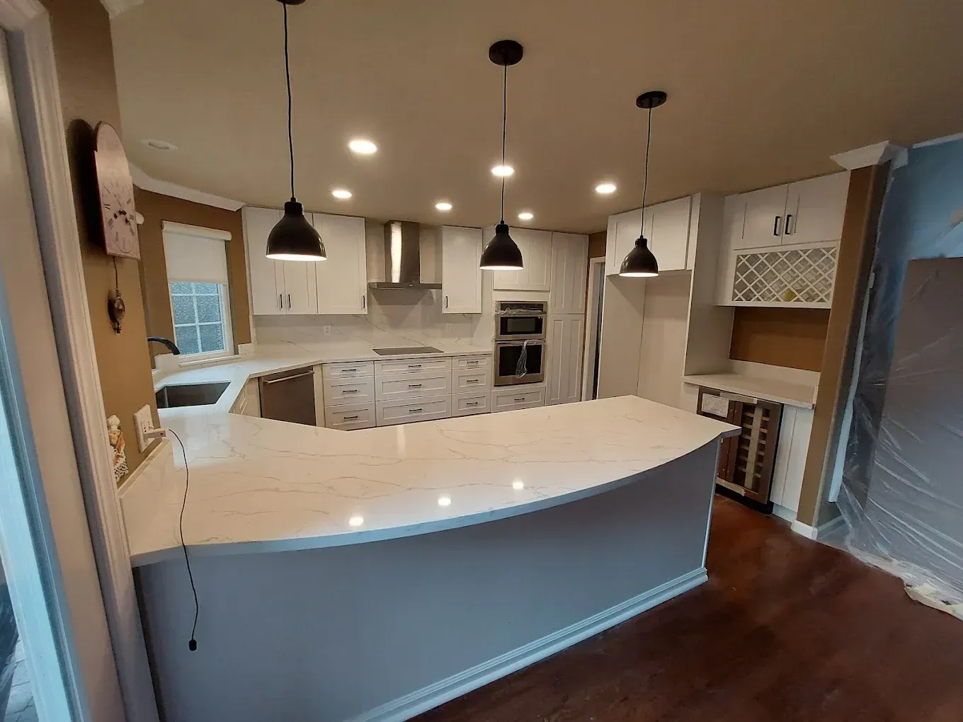 Newly renovated kitchen with white cabinets, quartz countertops, and three black pendant lights.