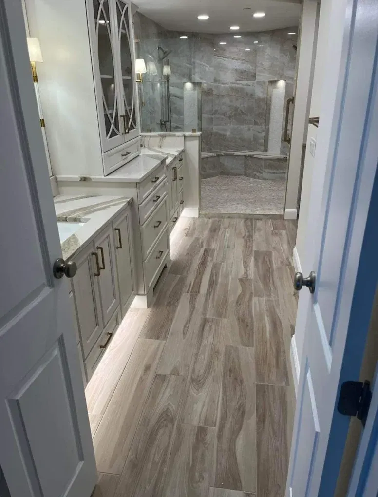 Bathroom with white cabinets, wood-look floor, and a walk-in shower.