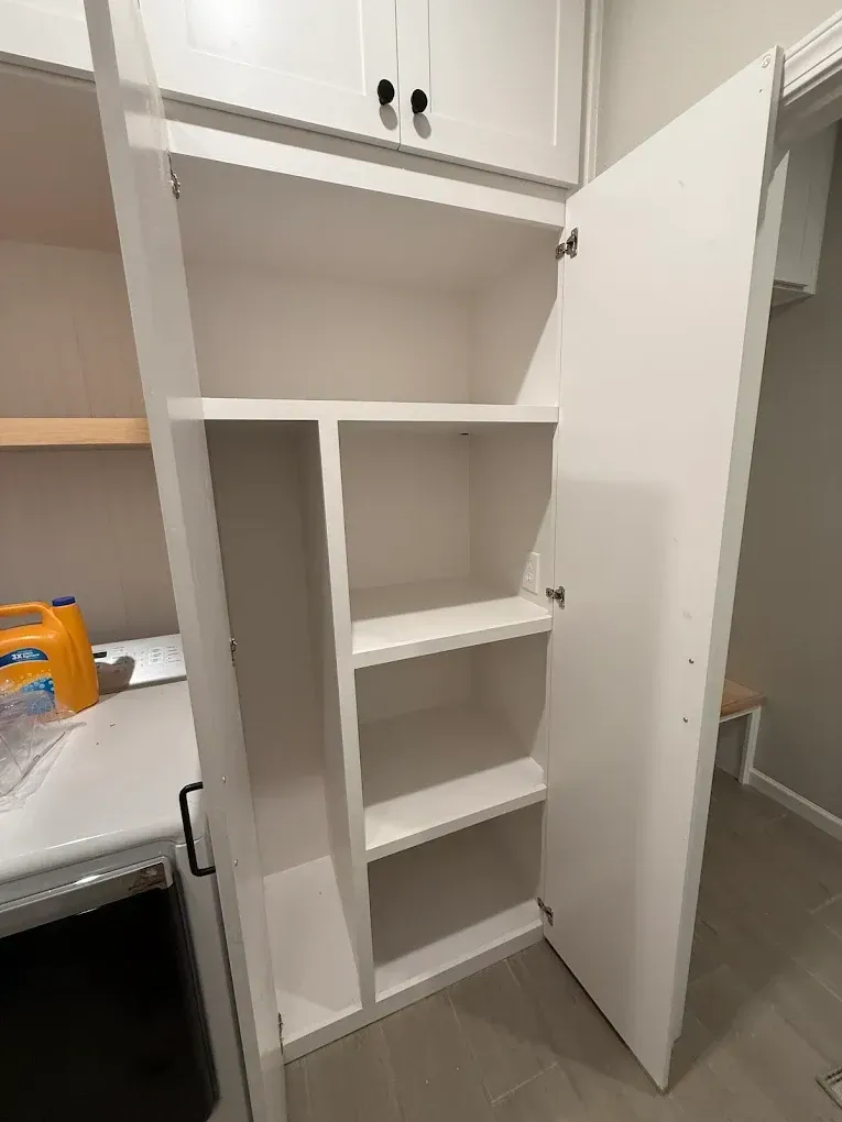 White laundry room cabinet with open door, showing shelves.