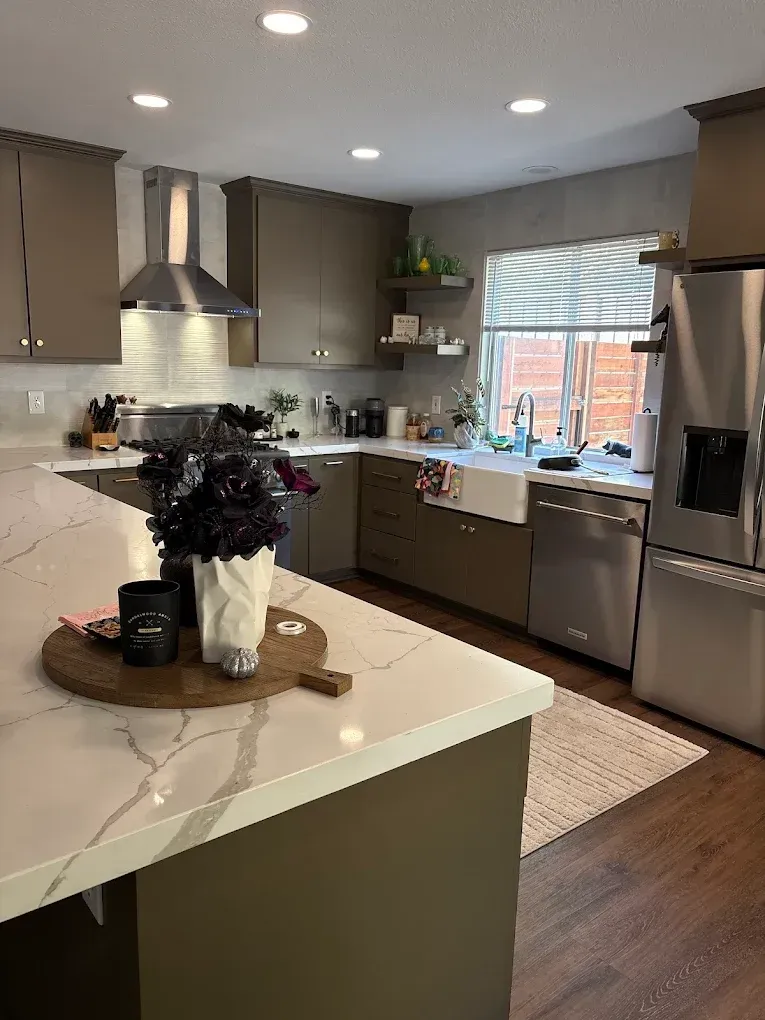 Modern kitchen with gray cabinets, white countertops, stainless steel appliances, and a floral arrangement.
