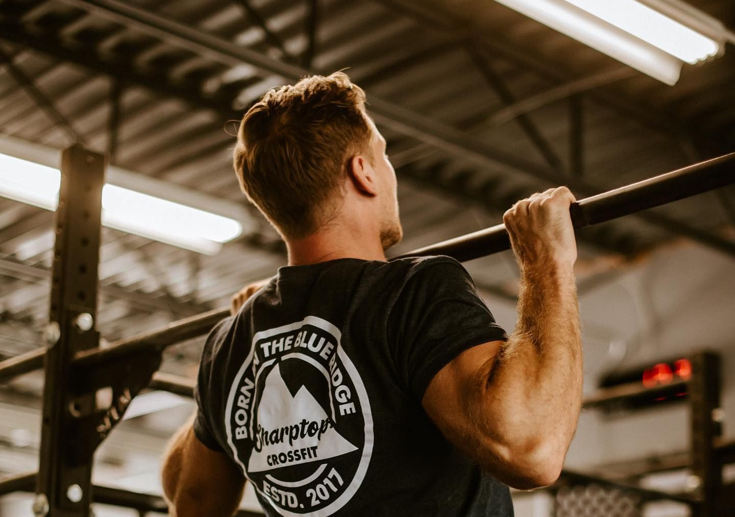 A man is doing a pull up on a bar in a gym.