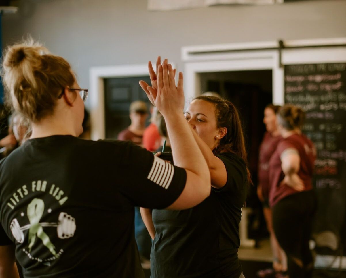 Two women are giving each other a high five in a gym.