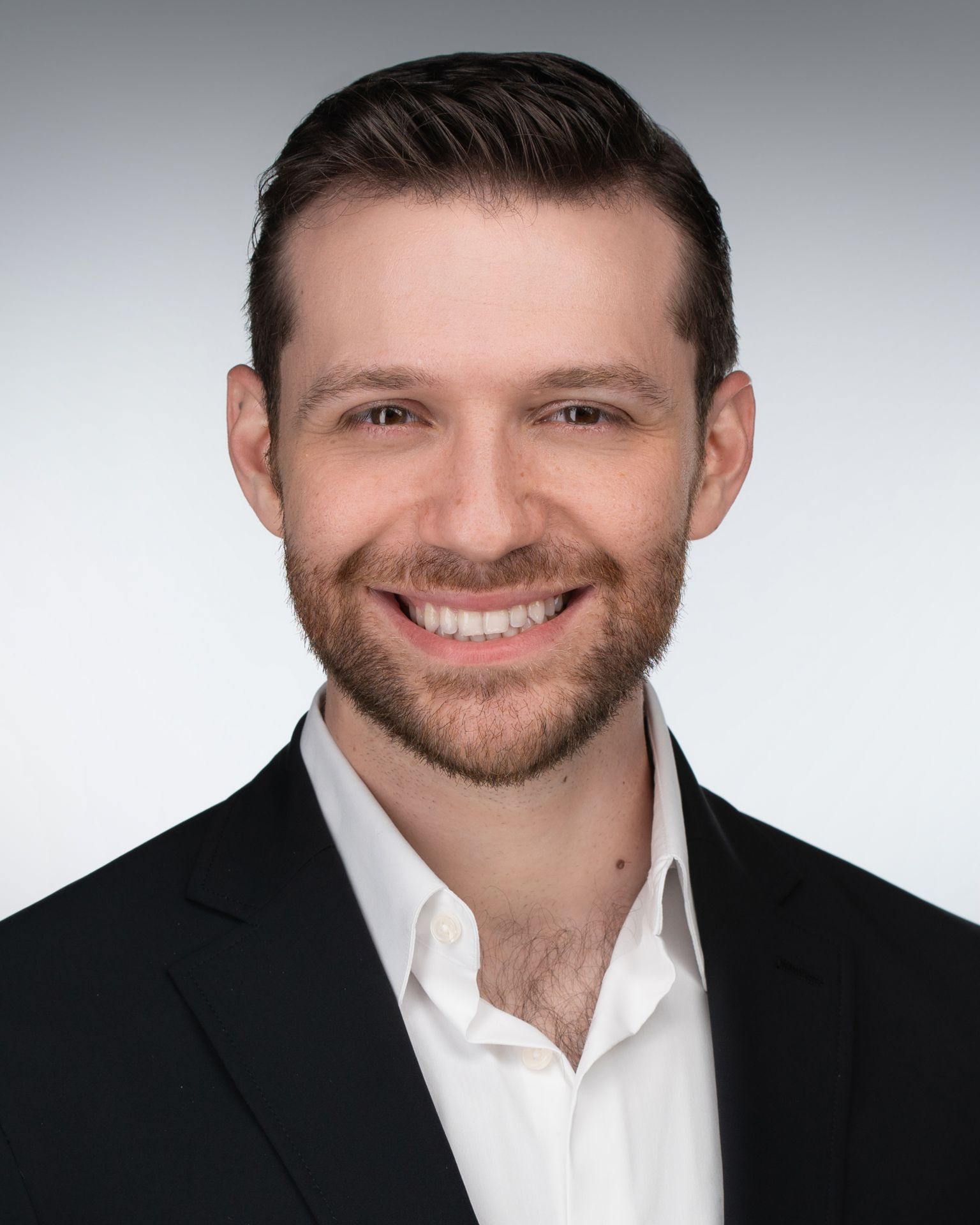 Modern business headshot of a male professional wearing a black blazer and open‑collar white shirt, photographed with clean studio lighting by Malena Vazquez for Art of Portraits – Miami Headshots & Portraits.