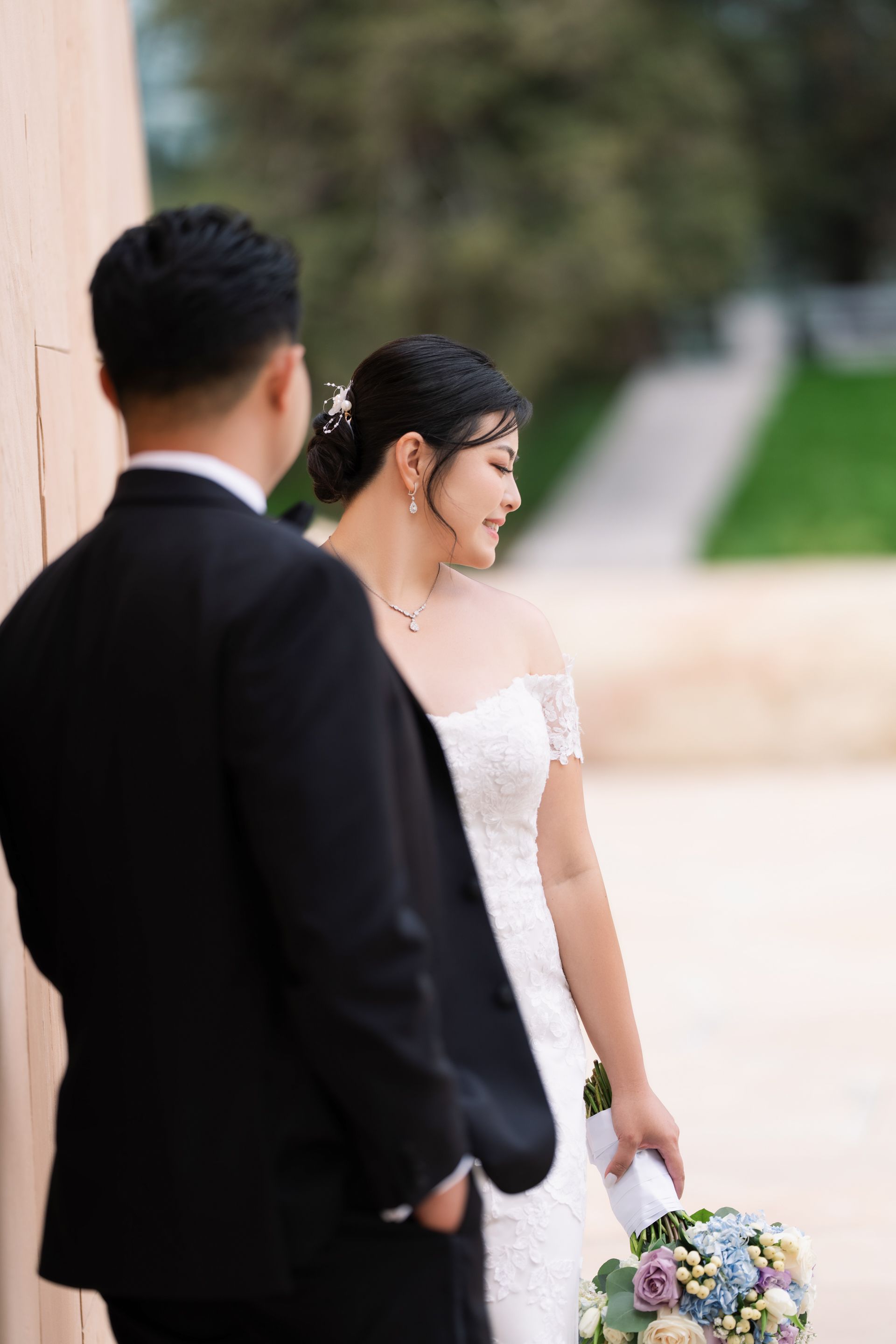 Romantic candid wedding portrait of bride and groom sharing intimate moment outdoors
