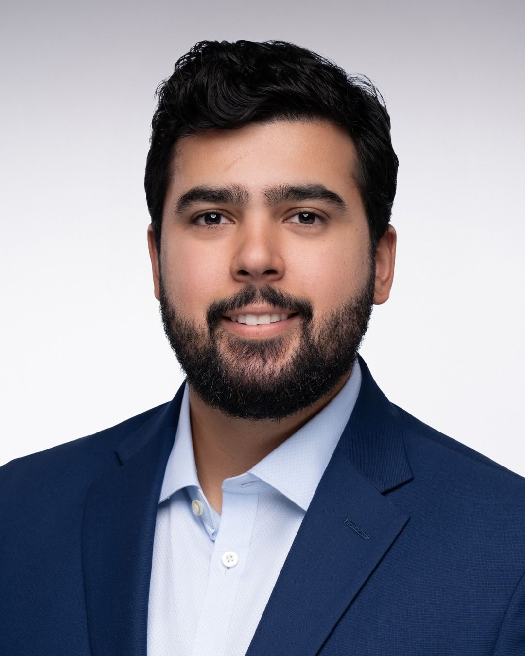 Professional headshot of a person wears blue navy jacket.