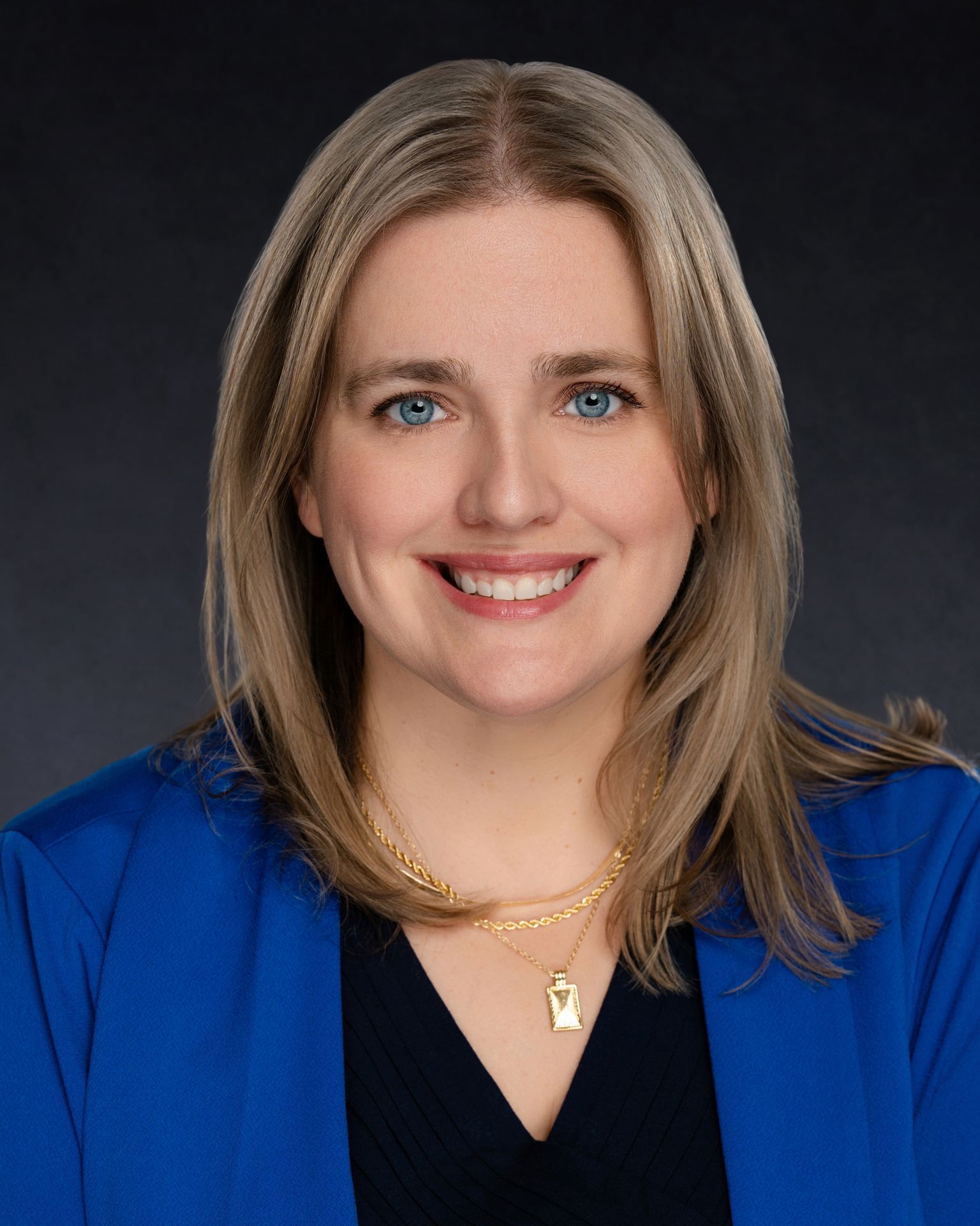 Professional headshot of a woman with black shirt and blue blazer.