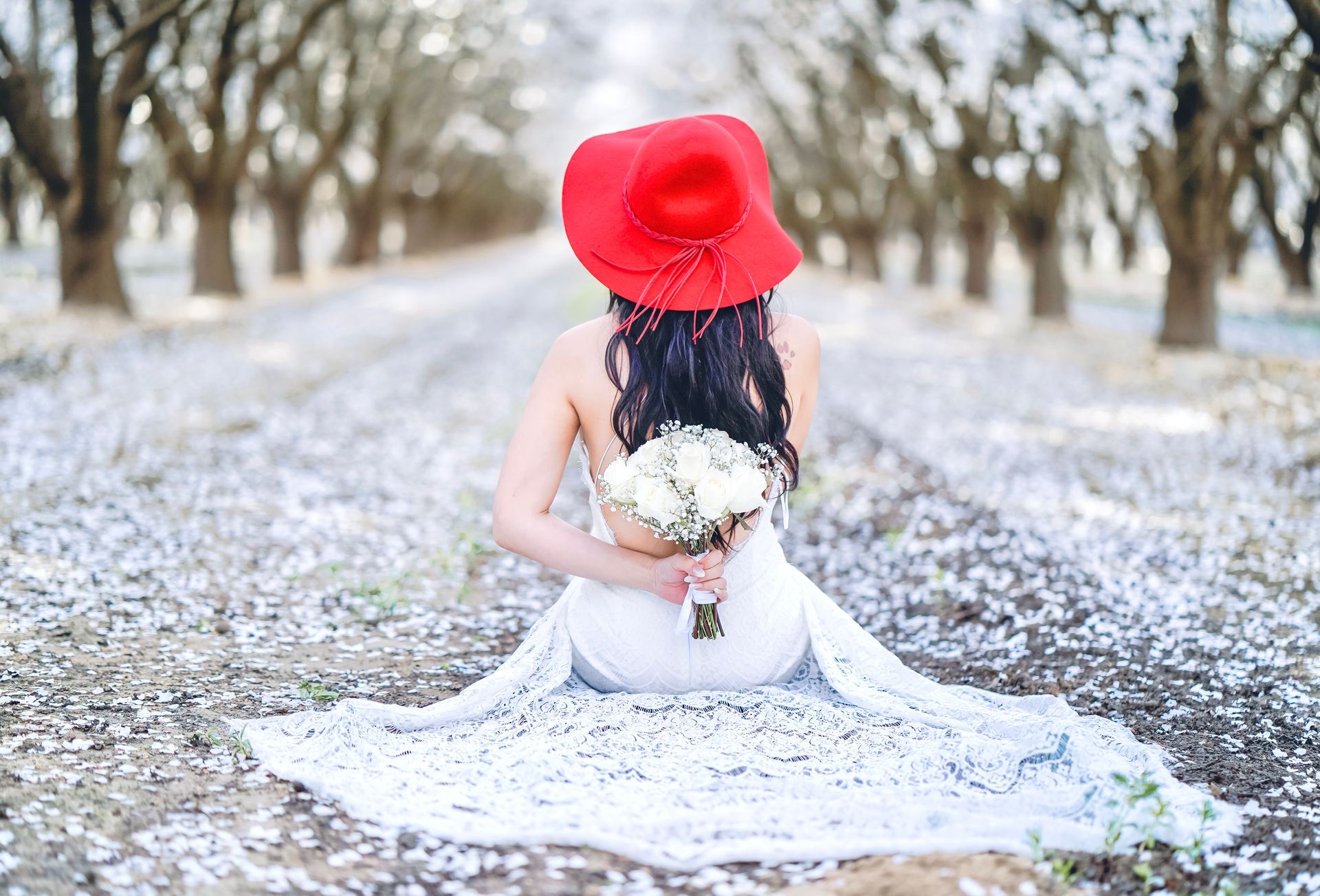 Garden Grove portrait photo of a woman siting and holding flowers behind her back.