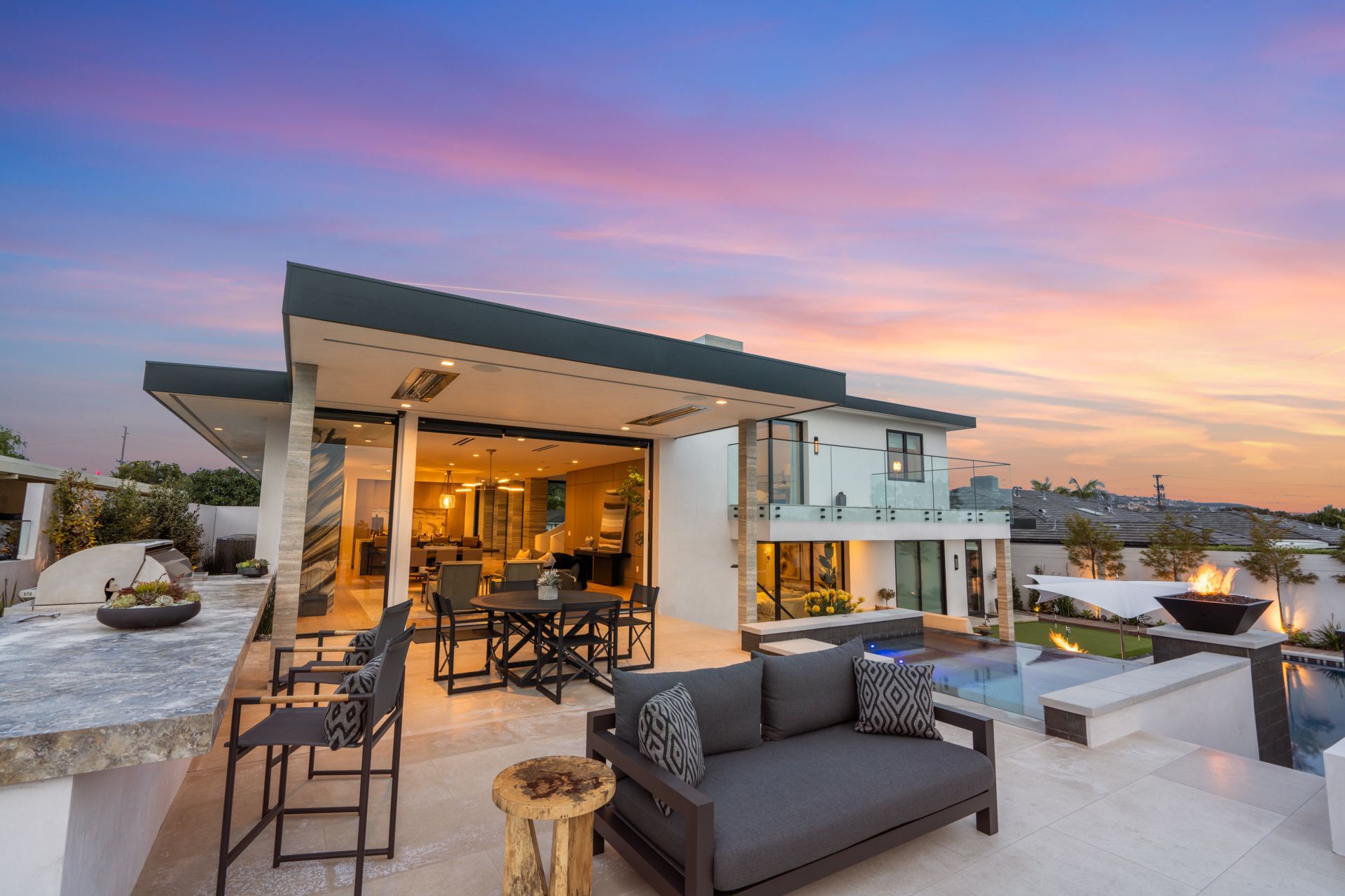 Luxury modern home exterior at sunset with outdoor patio and pool area