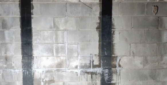 A brick wall with a black beam between two bricks.