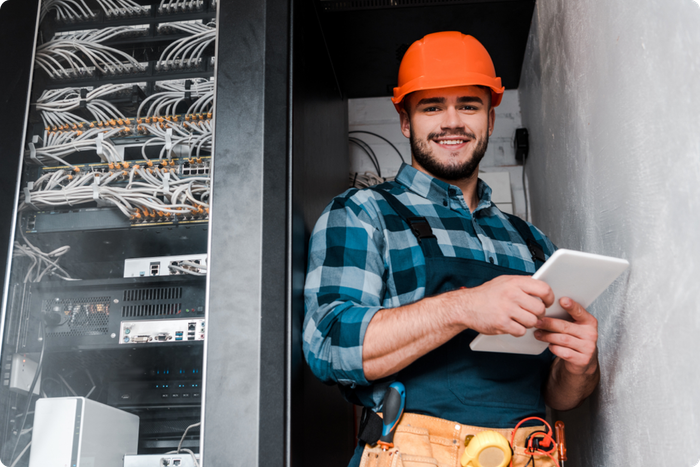A man wearing a hard hat is holding a tablet.