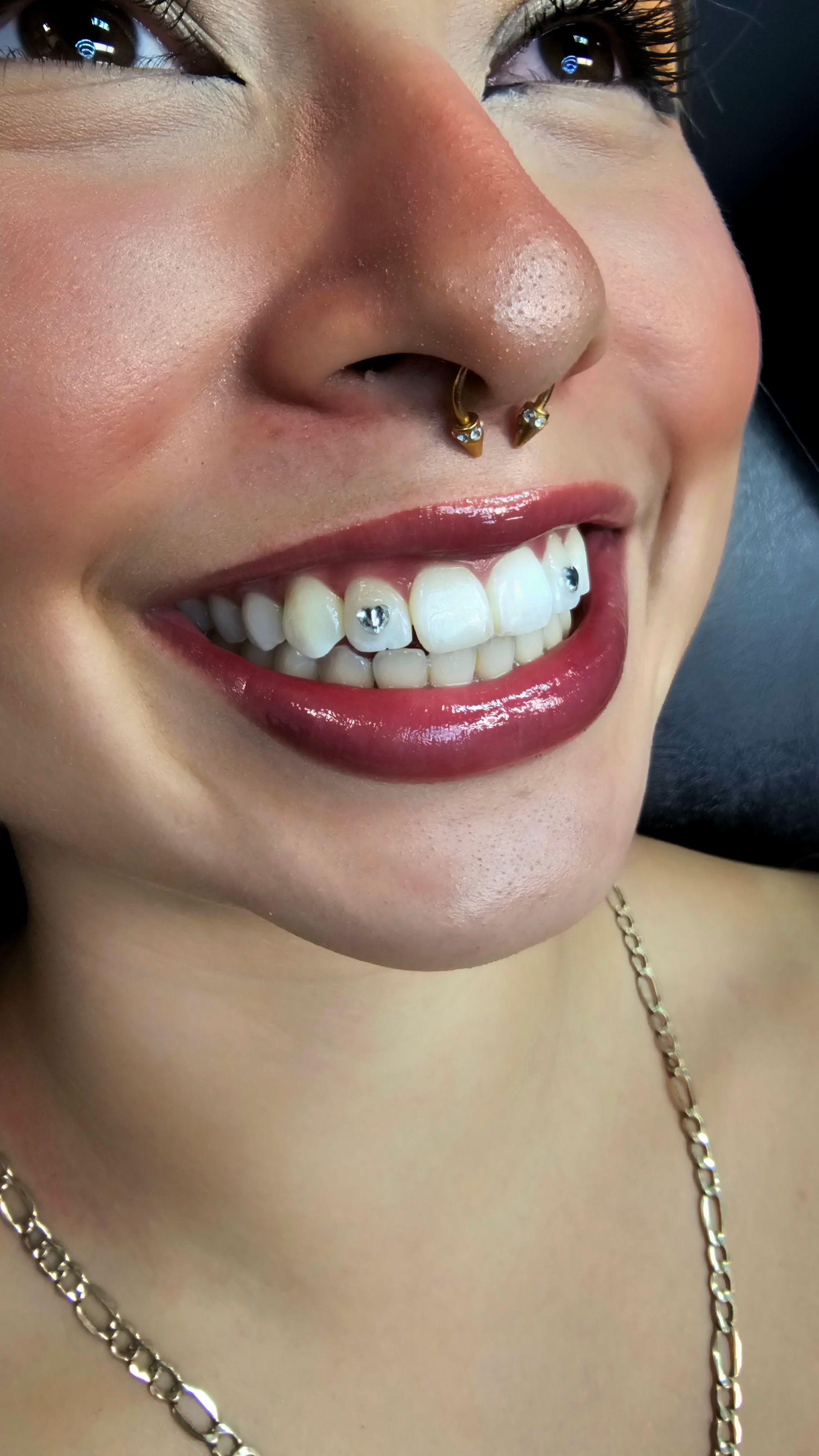 Tooth gem sparkling on a smile, applied by Ikonik Ink in Lakewood, CO