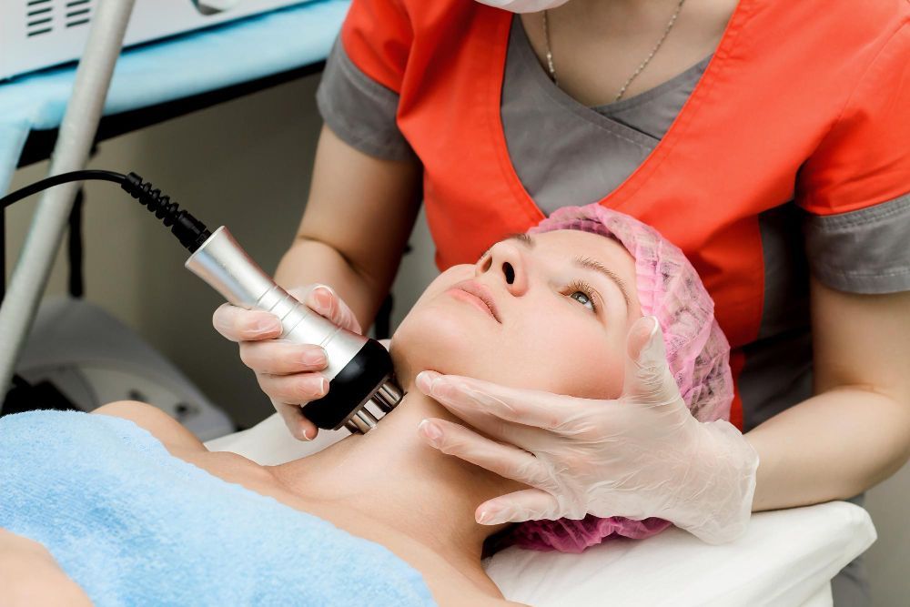 Cosmetic treatment on woman’s neck with handheld device in a clinic