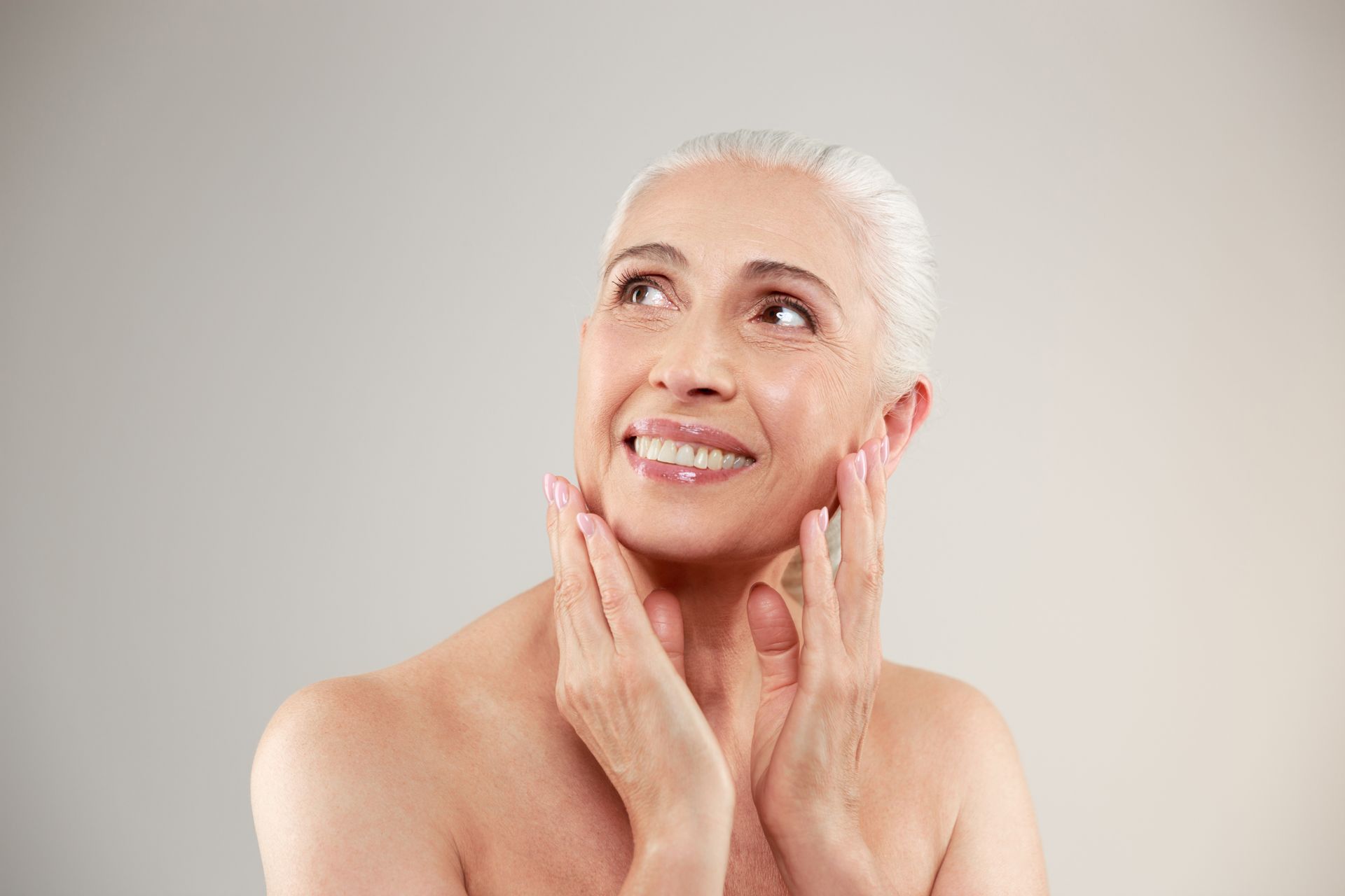 a woman with gray hair is smiling with her hand on her chin