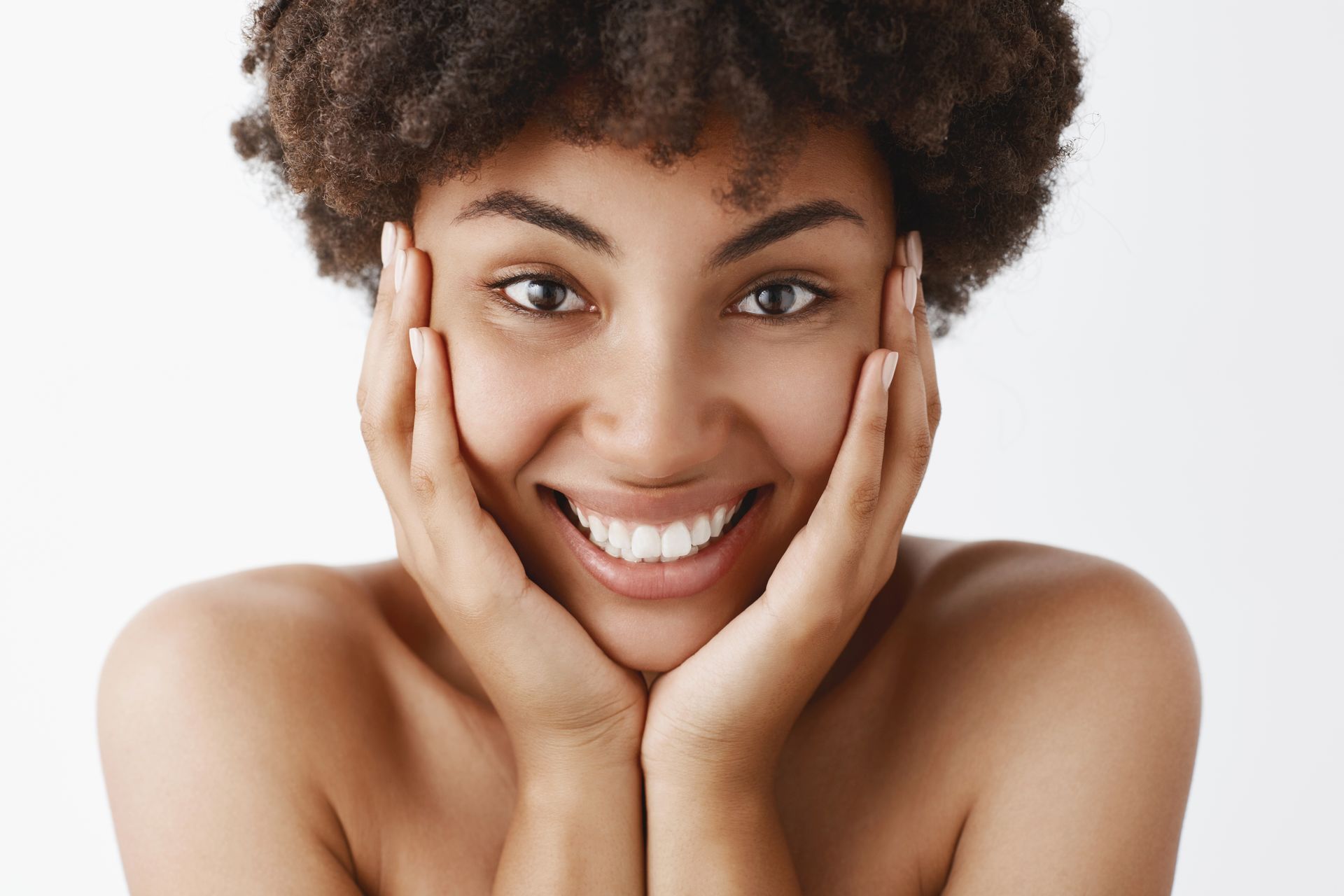 a woman is smiling with her hands on her face