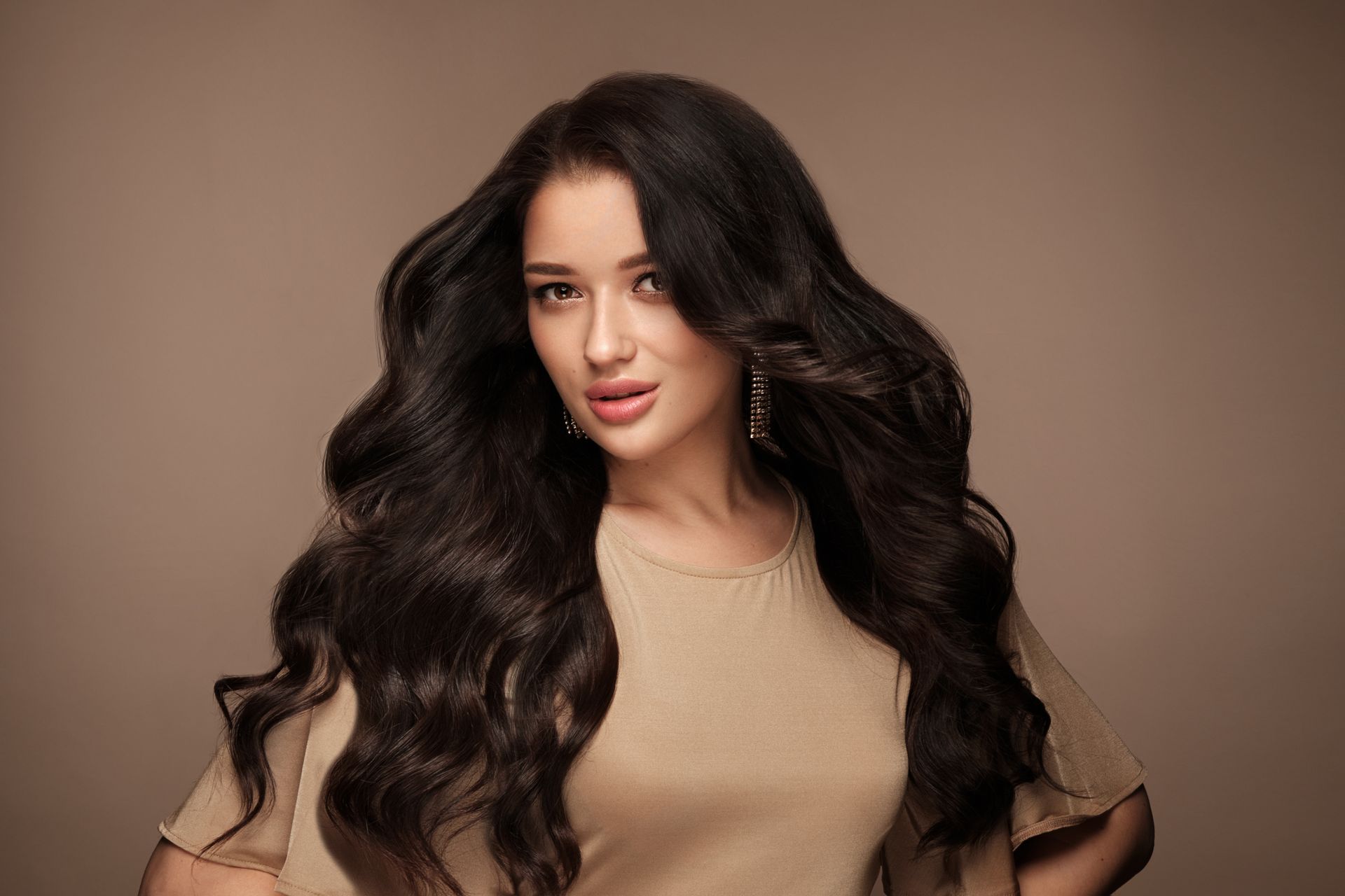 a woman with long dark hair is wearing earrings