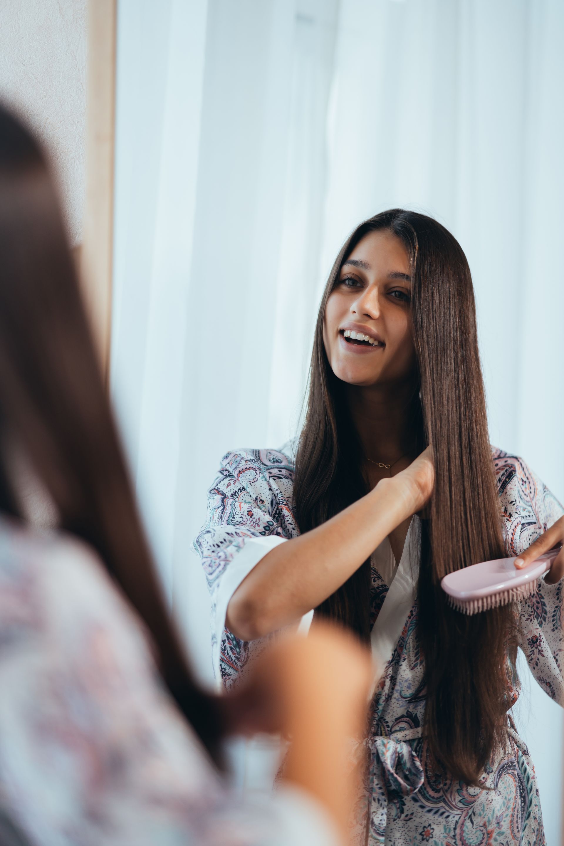 a woman brushing her hair in front of a mirror