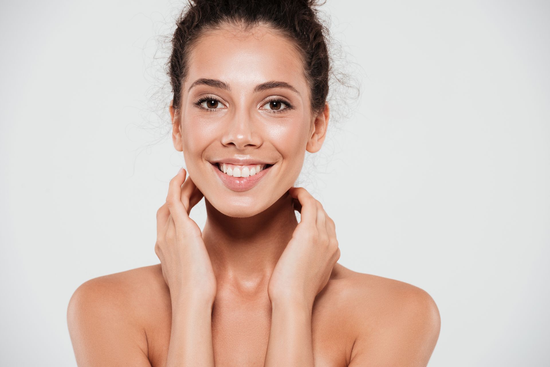 a woman is smiling and touching her face with her hands