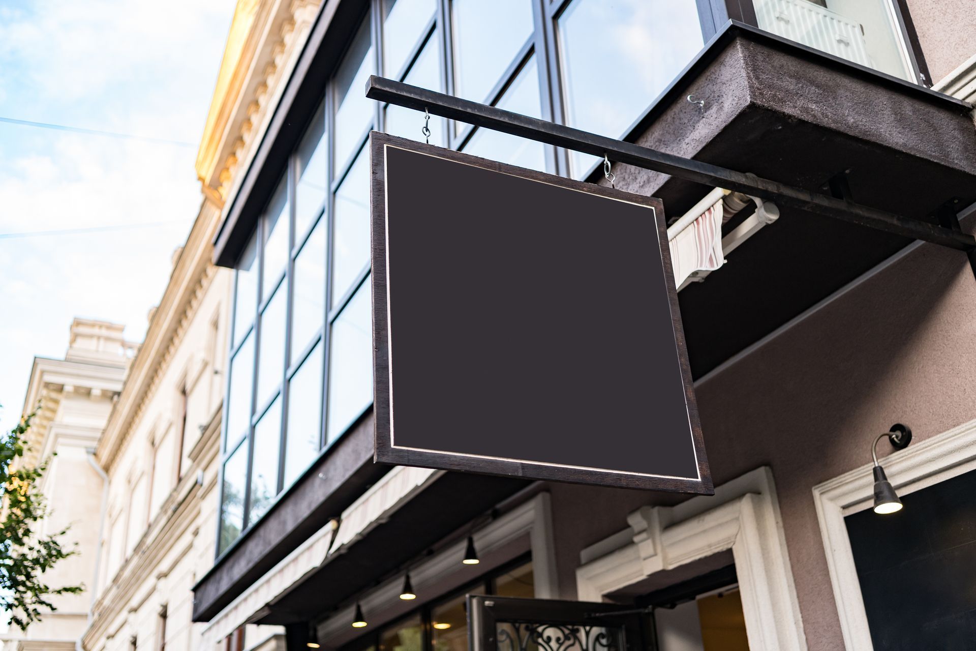 A black sign is hanging from the side of a building.