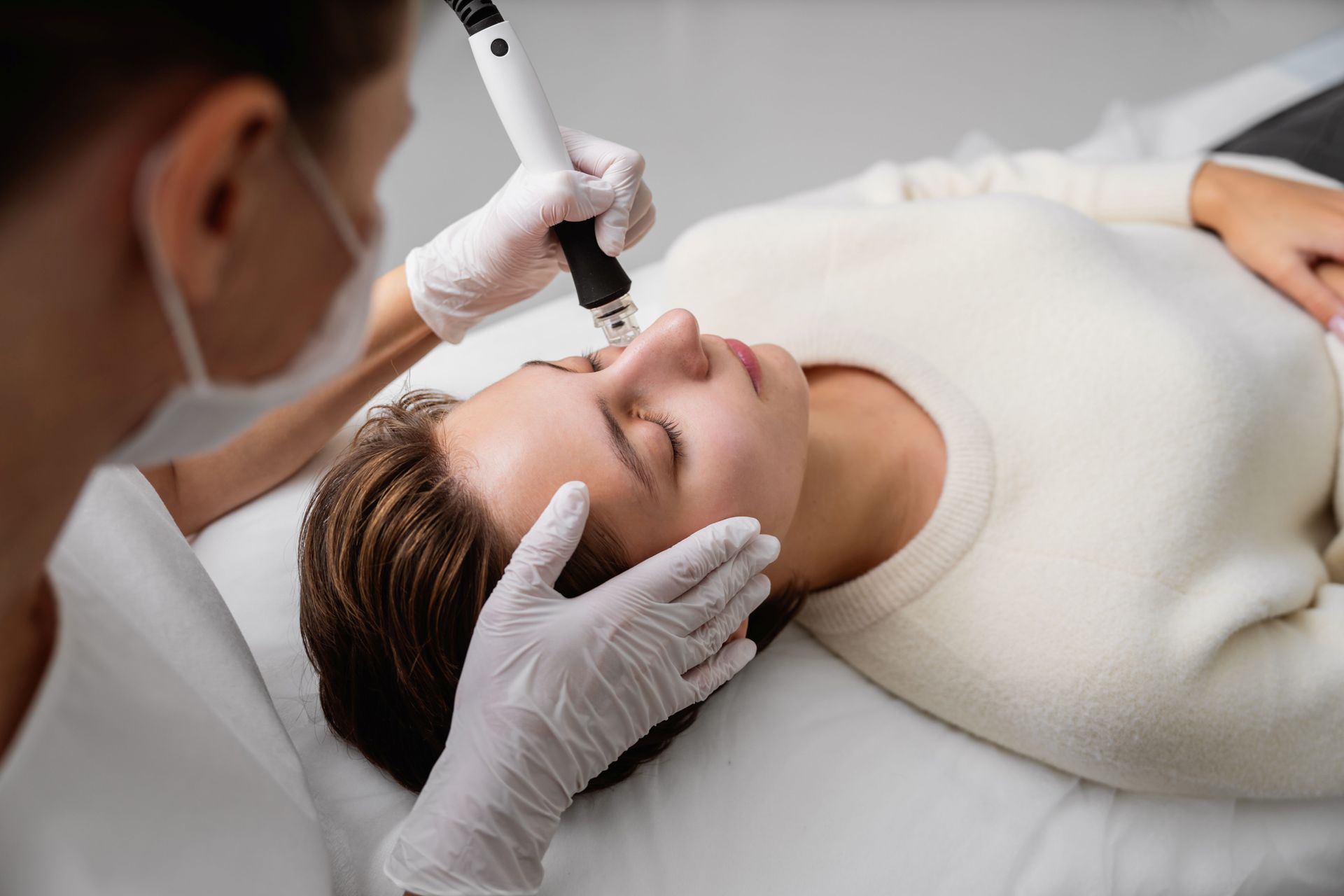 Cosmetologist applying facial treatment to a client lying on a spa bed