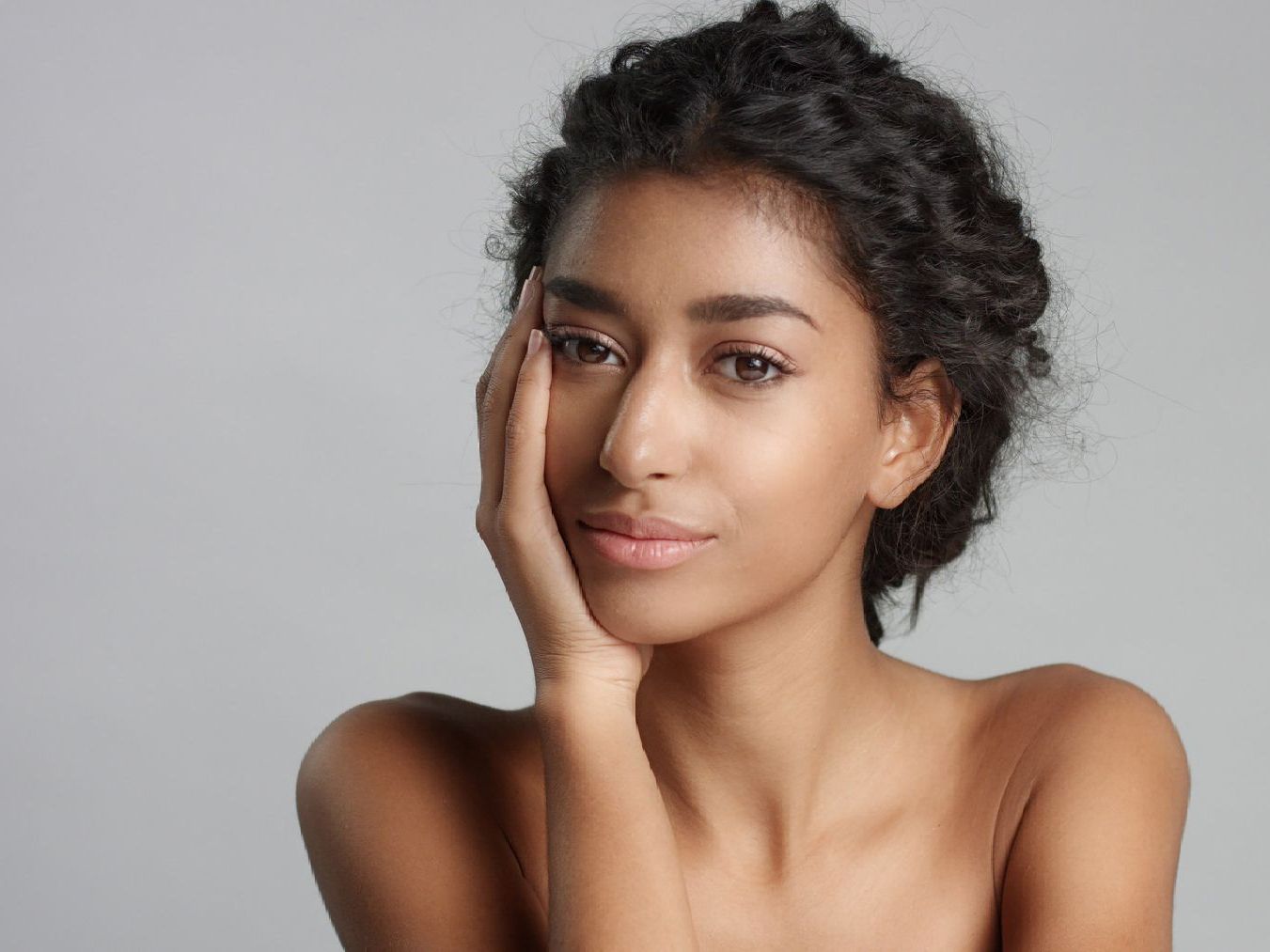 a woman with her hand on her face looks at the camera