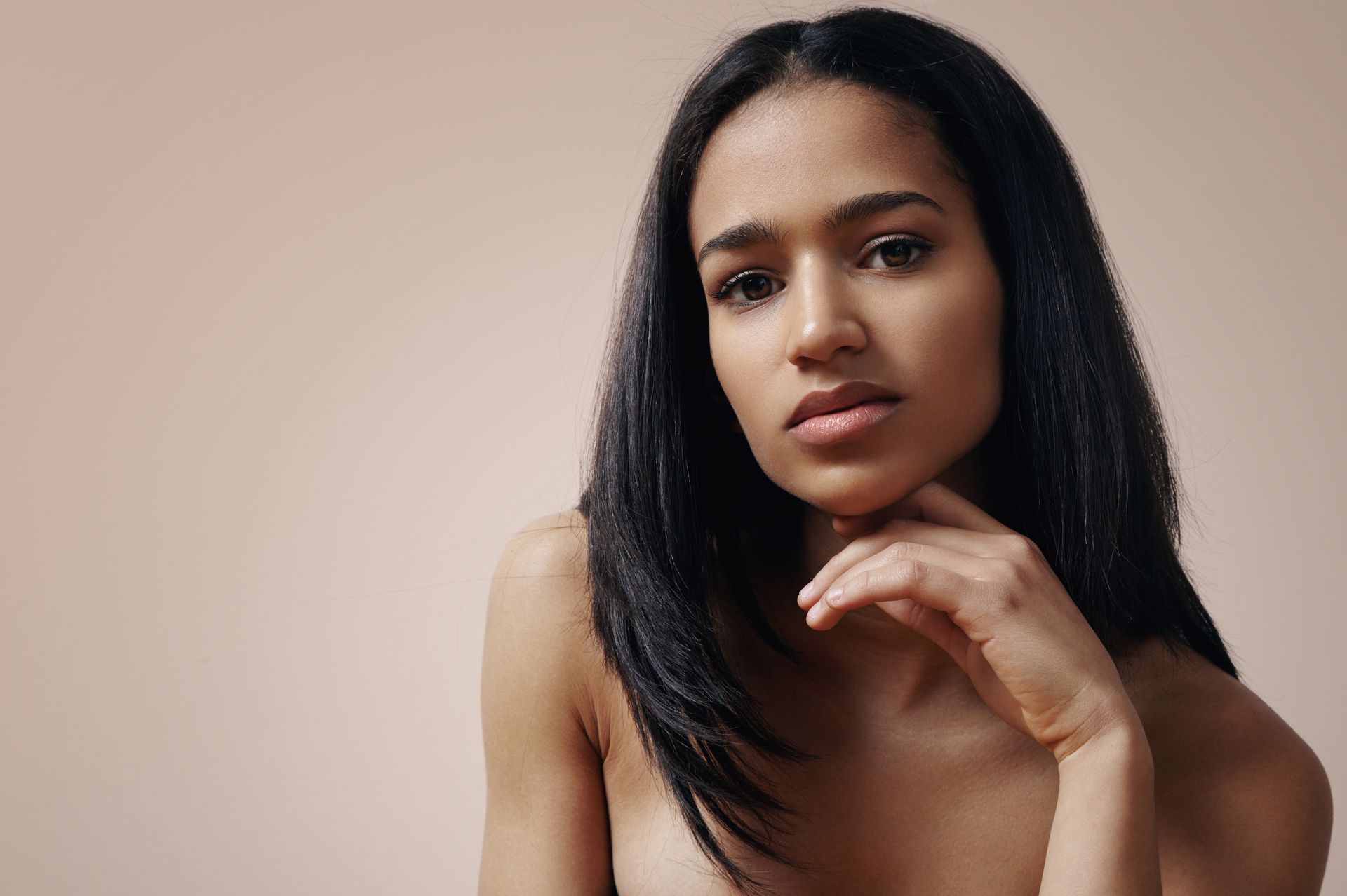 a woman with her hand on her chin looks at the camera