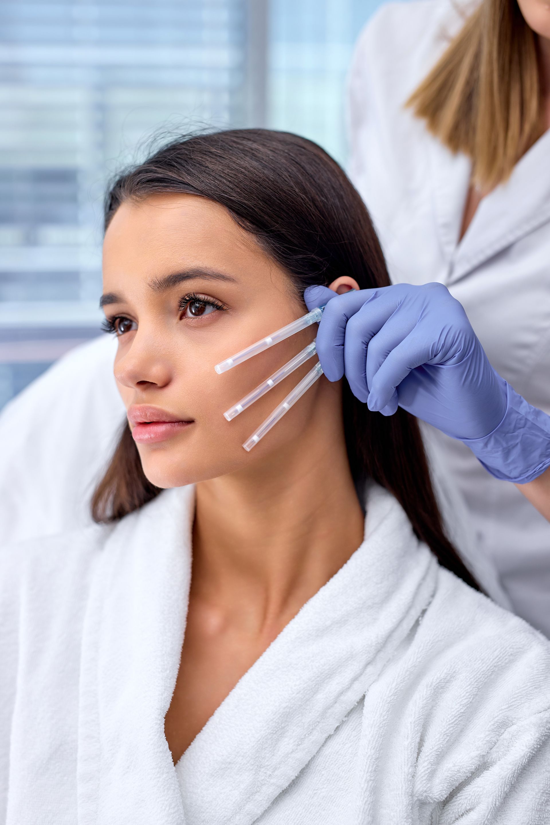 a woman in a white robe is getting injections in her face