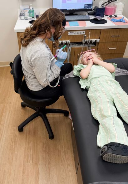 A young boy is sitting in a dental chair while a dentist examines his teeth.