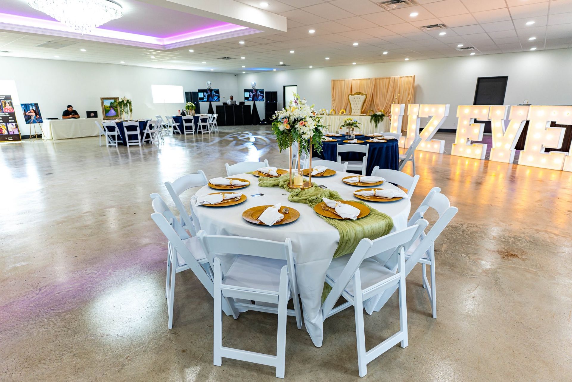 White round dining table set in a bright banquet hall with floral centerpiece and place settings
