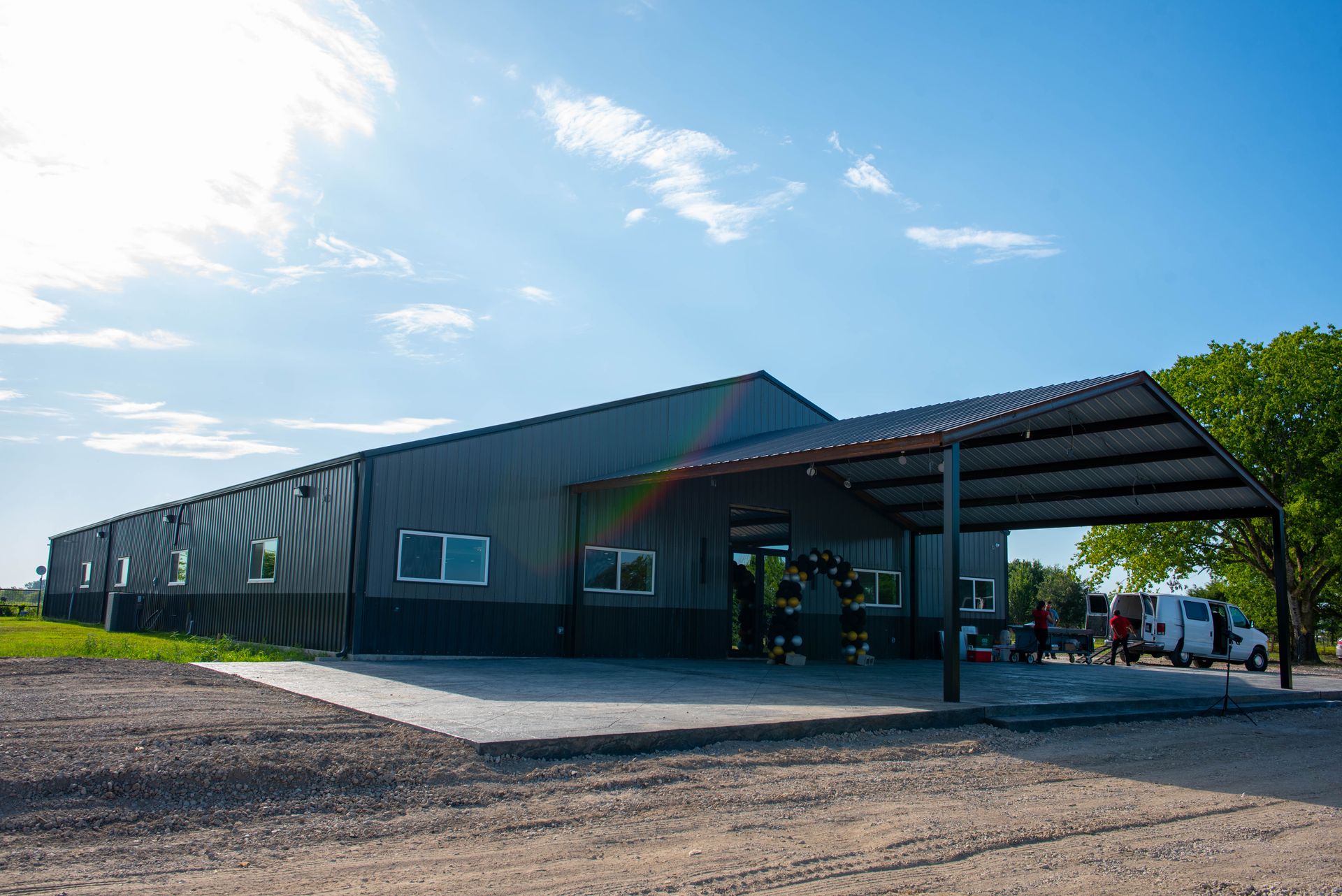 Long metal building with a covered entrance on a sunny day