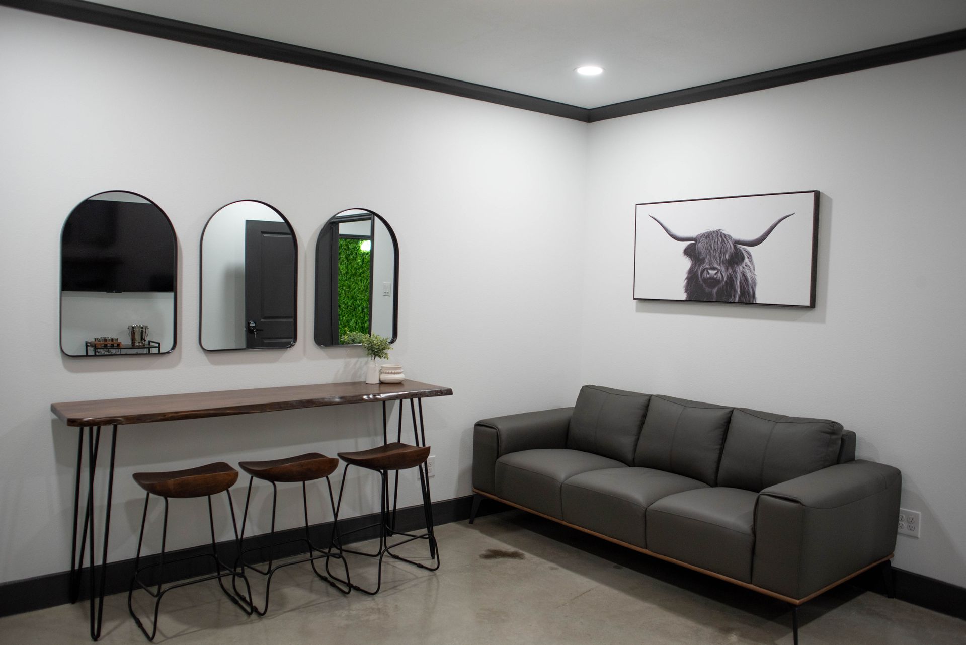 Modern living room with sofa, bar stools, wall mirrors, and minimalist decor