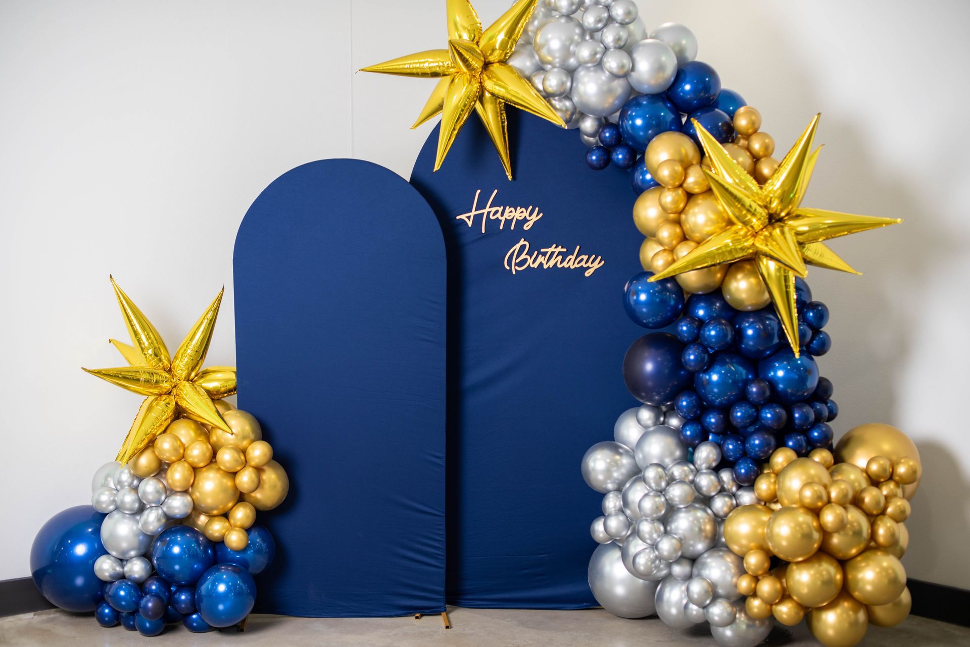 Blue and gold balloon arch with stars framing a navy 