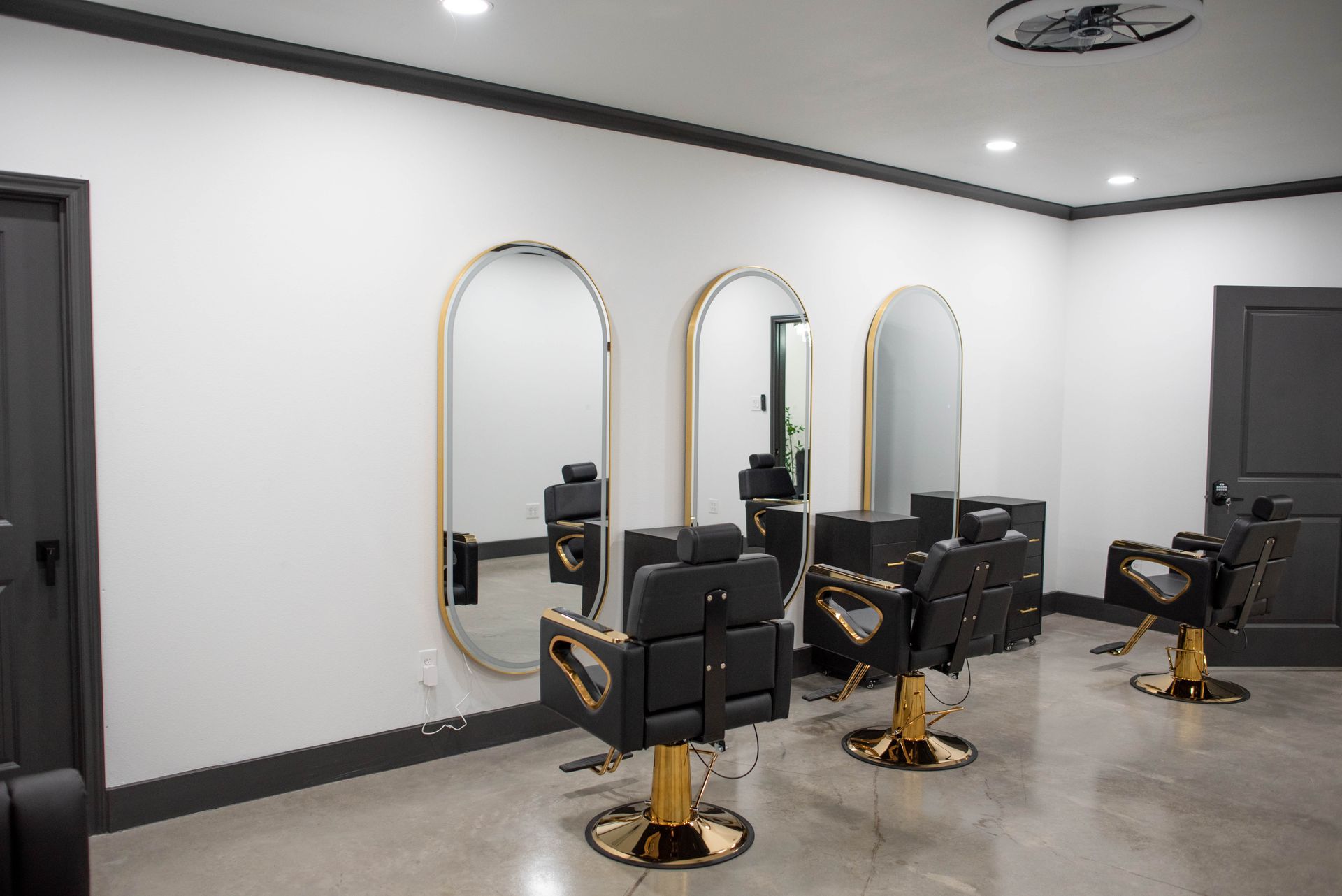 Modern barbershop with black chairs, gold-framed mirrors, and white walls