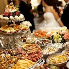 Elegant dessert buffet with tiered pastries, fruit, and flowers at a wedding reception