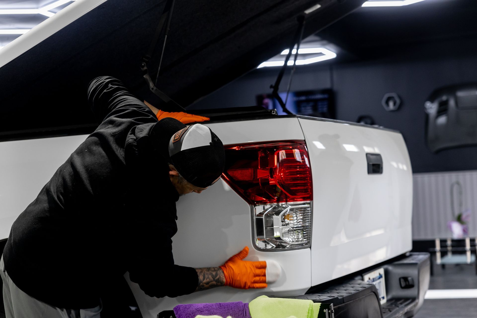 A man is cleaning the fender of a white truck.
