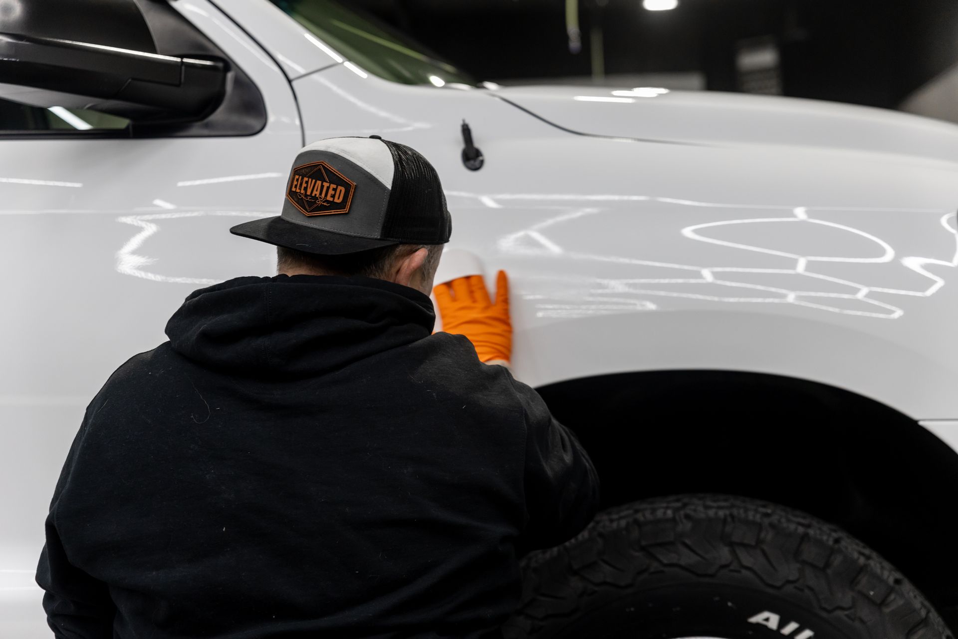 A man is cleaning the fender of a white truck.