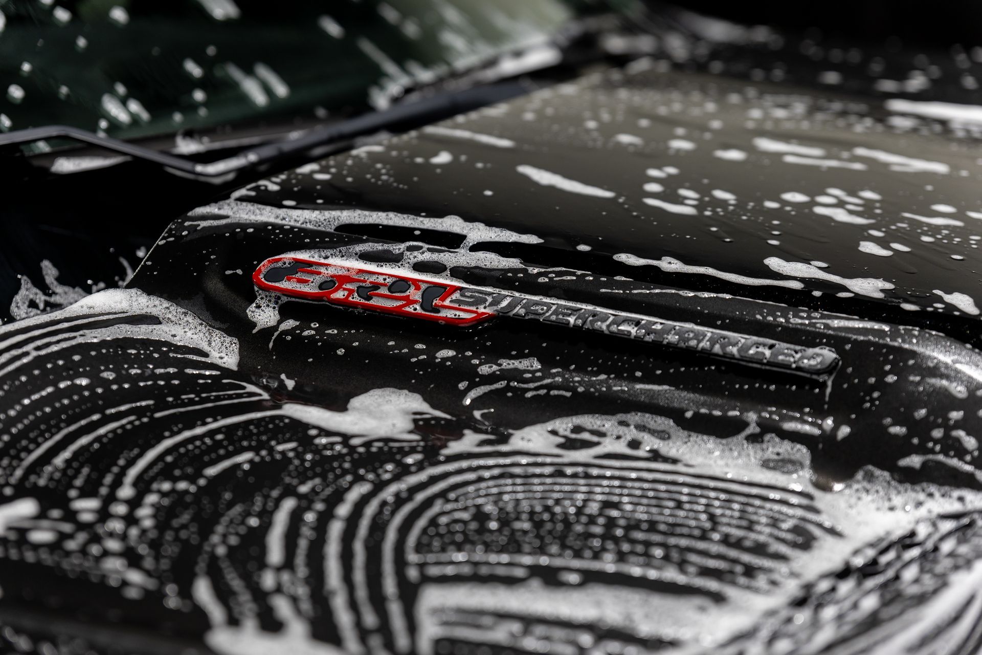 A black car is being washed with soap and water.