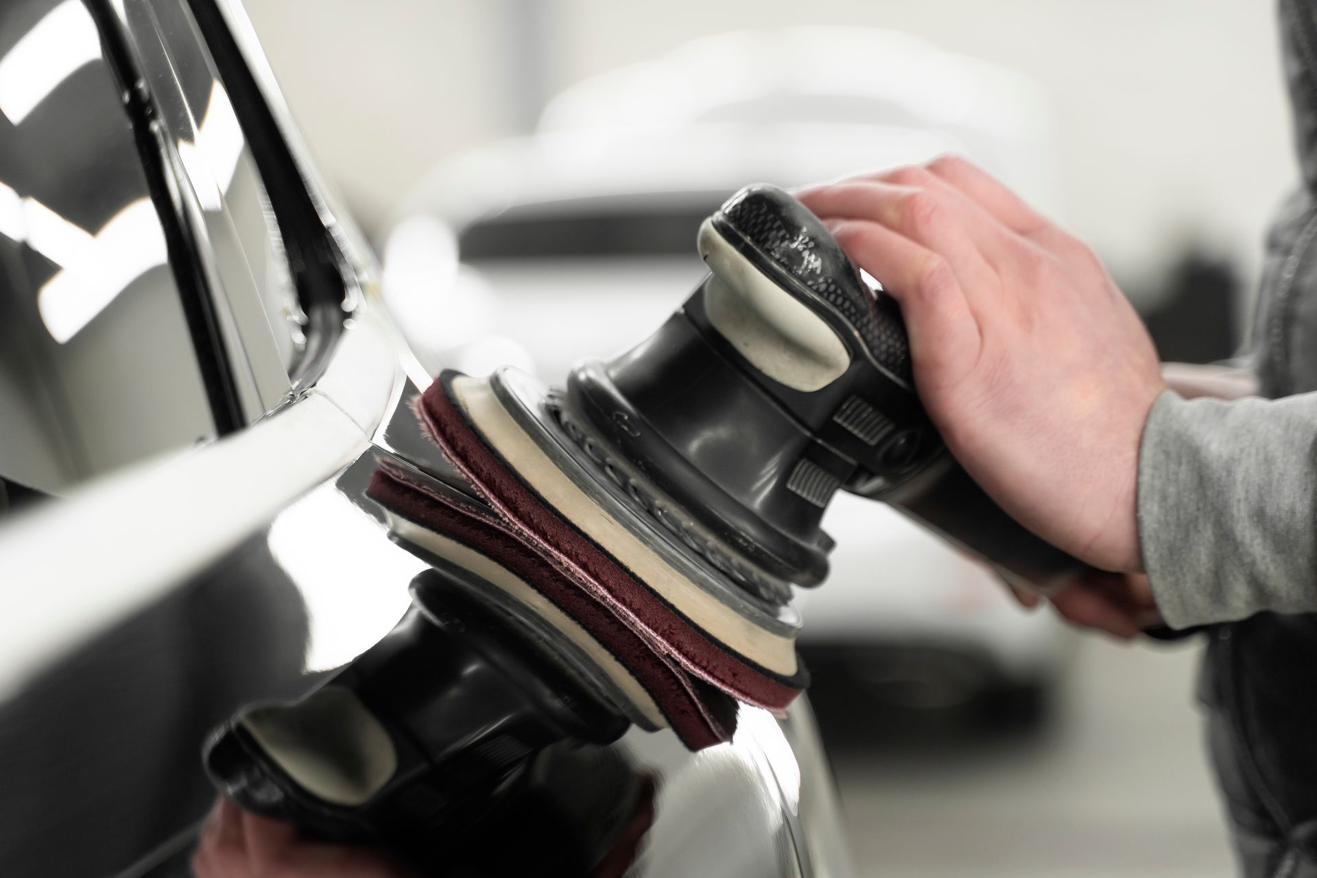 A person is polishing a car with a machine.
