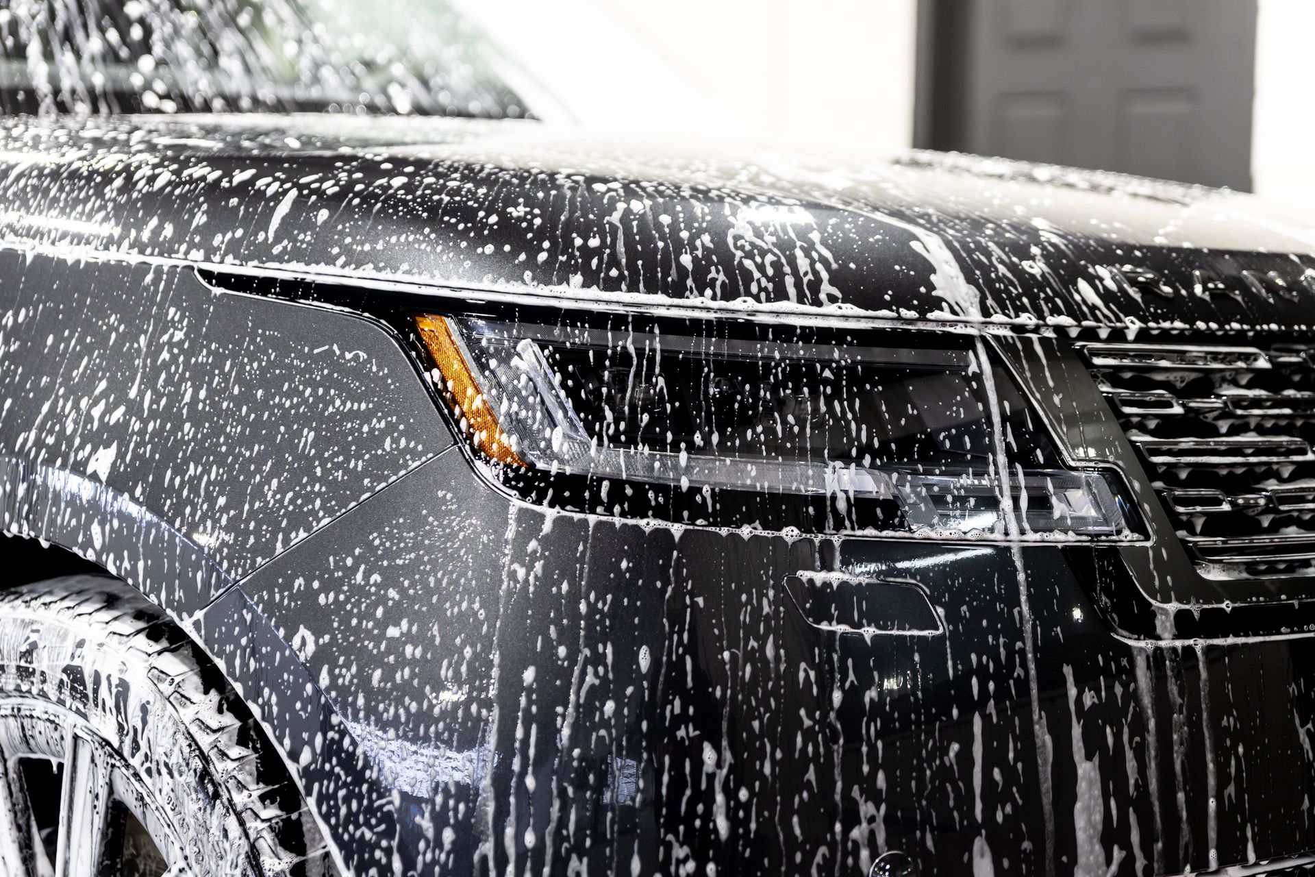 A man is washing a car in a garage.