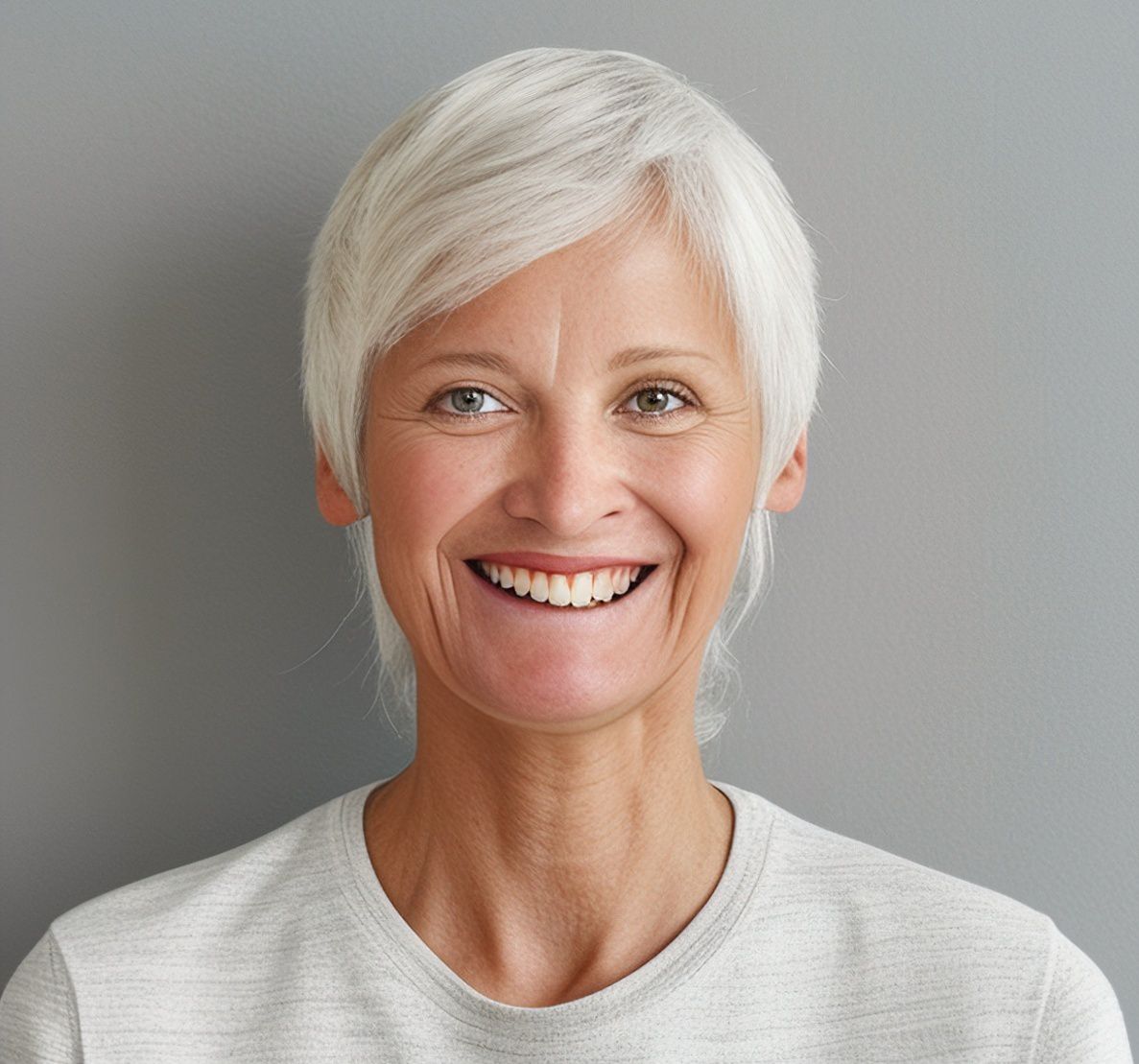 Woman with short, white hair smiles broadly at the camera.