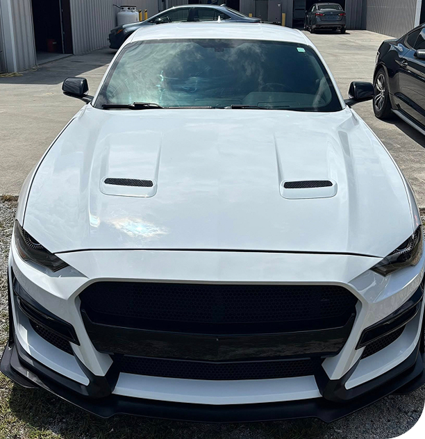 White sports car with black accents, hood scoops, and front splitter.